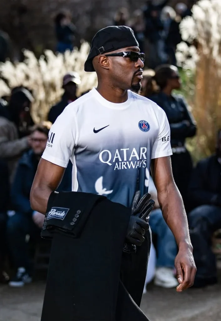 Model wearing the Art Basel Qatar pre-match shirt and sunglasses outdoors in Paris.