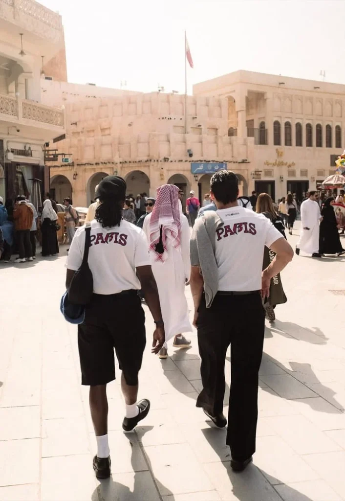 Group walking through Doha wearing PSG pre-match shirts with PARIS lettering on the back.