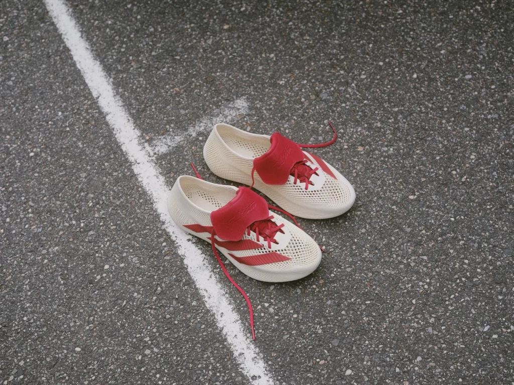 Cream lattice TW CLIMACOOL shoes with red stripes, laces and folded tongues on a court.