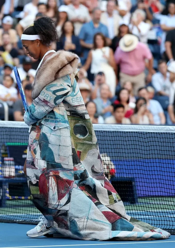 Naomi Osaka arrives on court in a painted KidSuper coat with a long train
