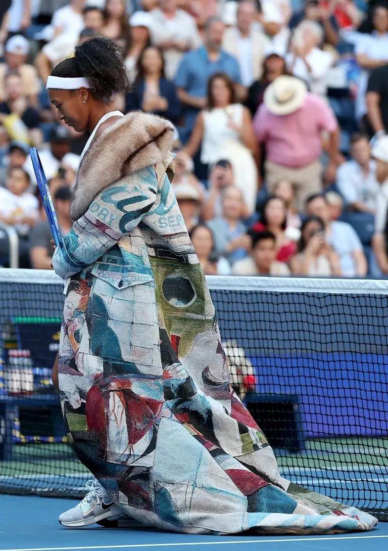 Naomi Osaka arrives on court in a painted KidSuper coat with a long train