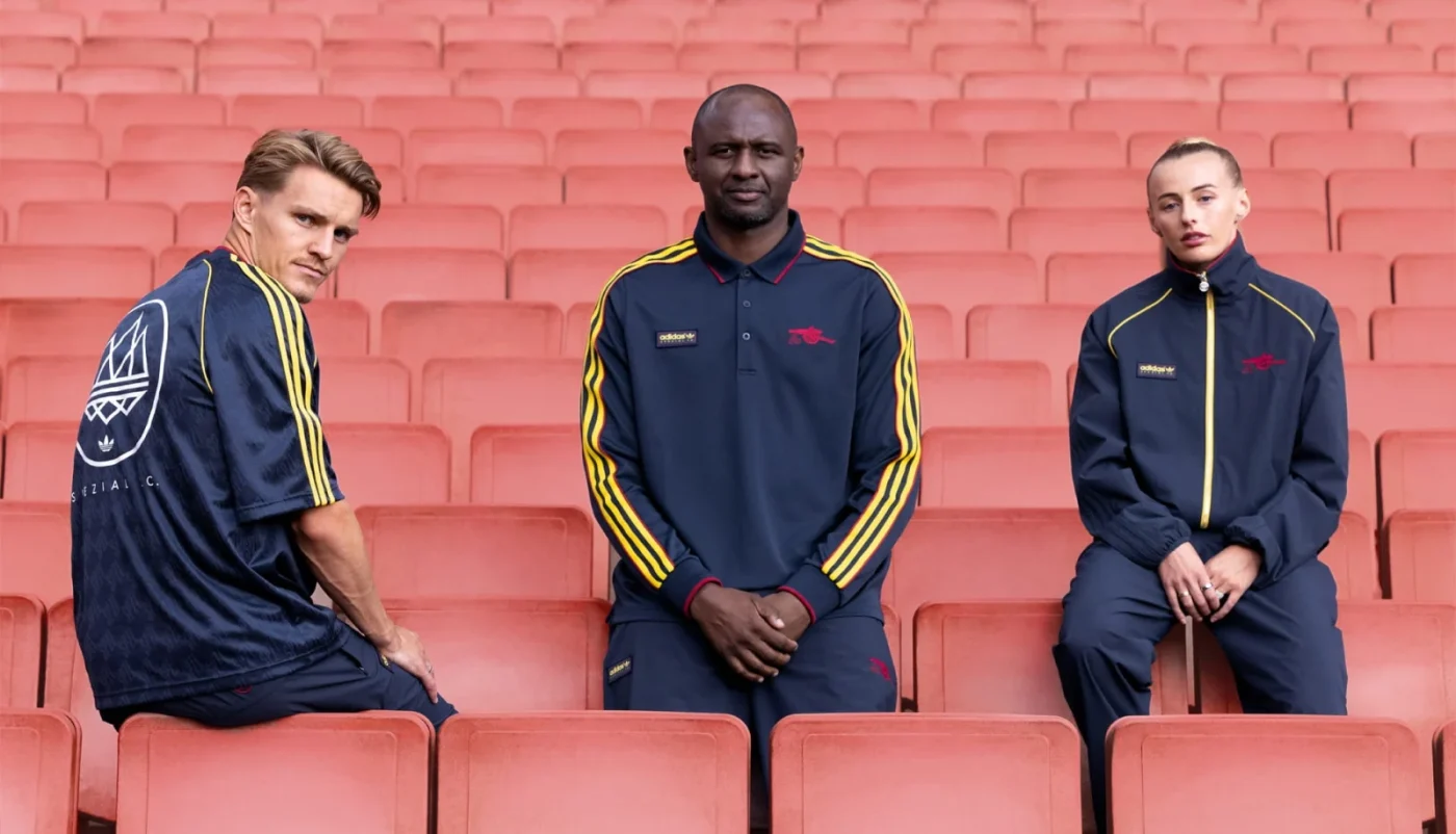 Martin Ødegaard, Patrick Vieira and Chloe Kelly in Arsenal adidas SPZL tracksuits on red stadium seats