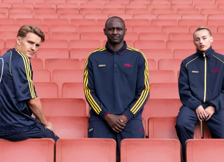 Martin Ødegaard, Patrick Vieira and Chloe Kelly in Arsenal adidas SPZL tracksuits on red stadium seats