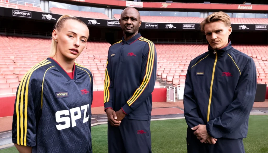 Chloe Kelly in an Arsenal SPZL jersey with Patrick Vieira and Martin Ødegaard behind her