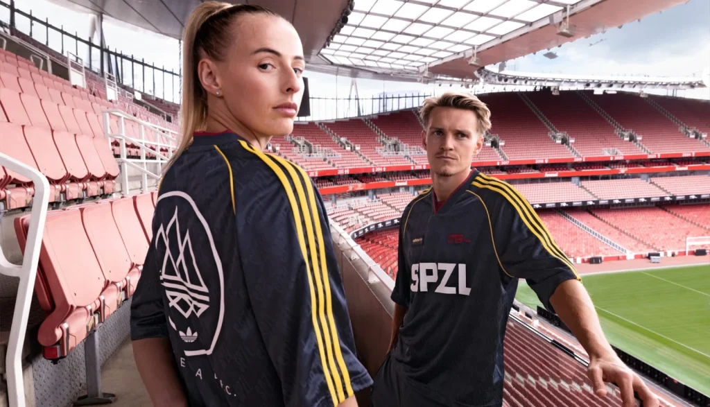 Back of Chloe Kelly’s navy SPZL shirt showing a white Trefoil and circular SPZL FC graphic