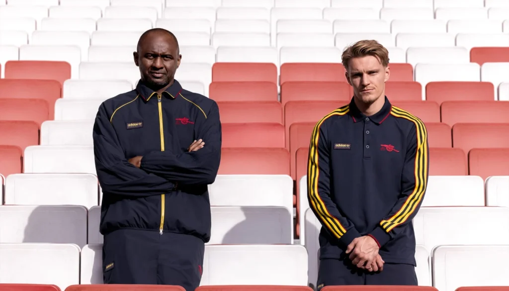 Patrick Vieira and Martin Ødegaard wearing navy and yellow Arsenal SPZL track jackets